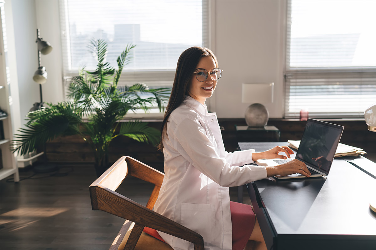 Smiling professional working on a laptop, representing orthopedic SEO strategies to improve Google rankings in 2024.