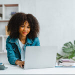 Professional woman using a laptop to schedule appointments online, illustrating the importance of online scheduling for orthopedic practices.